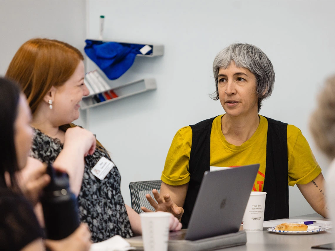 University of Arizona faculty and colleagues sit around a table in a collaborative meeting, discussing teaching practices in a supportive, academic setting.