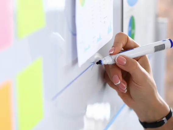 A faculty taking notes on a dry erase board for a course.