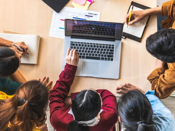 A group of five students collaborate on a group assignment.