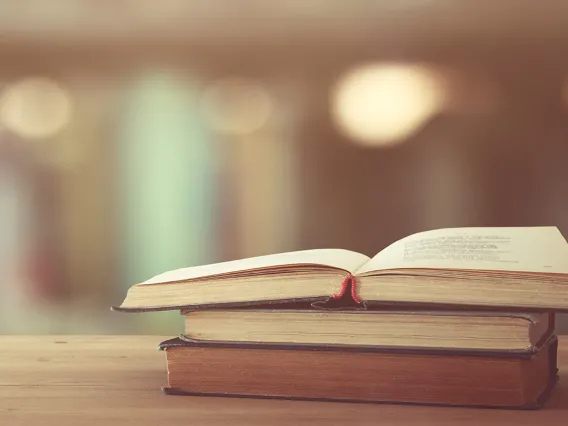 A stack of two books with an open book on top of them.