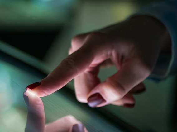 A close-up of a female hand interacting with a touch screen interface.