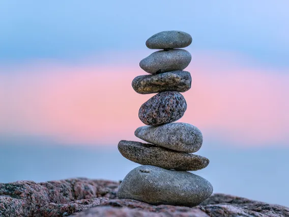 A pile of rock cairns sits there with a blue sky in the background.