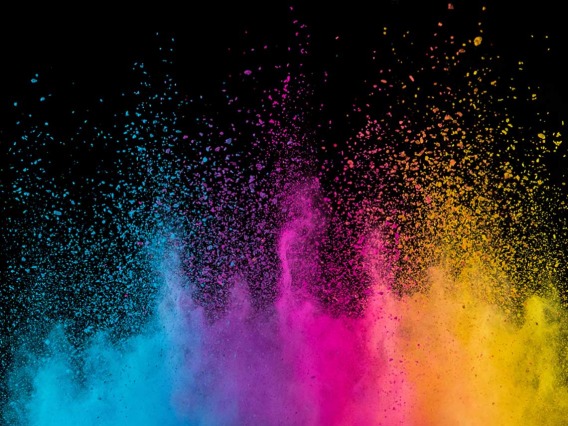 A gradient of powder color dust is being propelled into the air in a dark room.