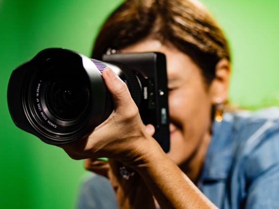 A multimedia member is taking a digital photo in a green screen studio