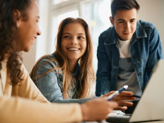 A couple students laugh while they collaborate on a task at a coffee shop.