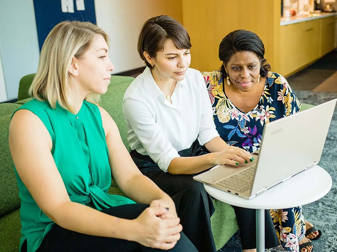 A group of faculty members are discussing their course design options while building their online course on their laptop device.