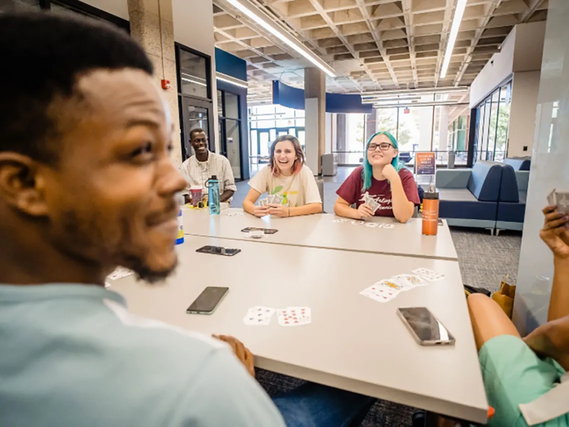 A group of young individuals play a game of cards as part of one of the special interest groups activities.