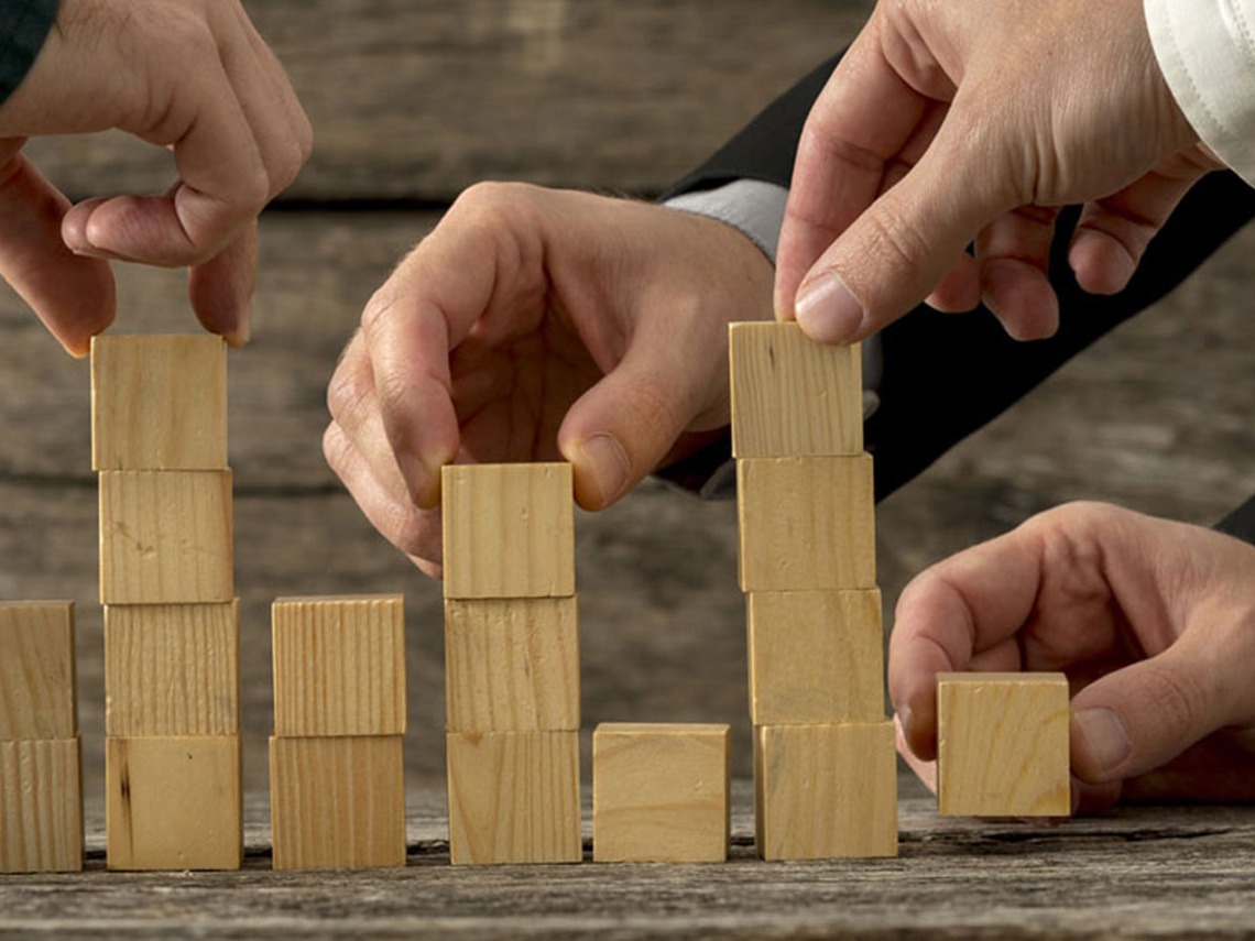 A group of people are arranging a set of wooden cubes on a table.