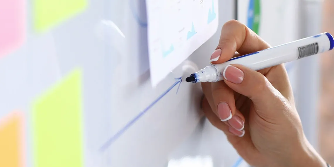 A faculty taking notes on a dry erase board for a course.