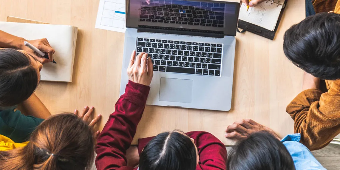 A group of five students collaborate on a group assignment.