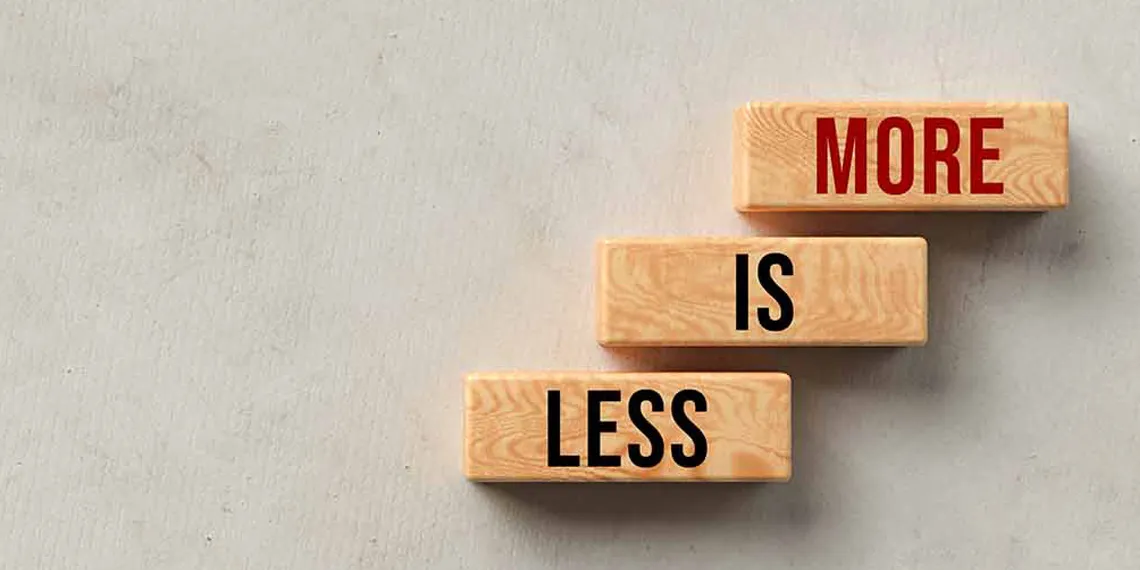 Three wooden rectangles sit on gray background. Each rectangle contains one of the following three words, Less is More.