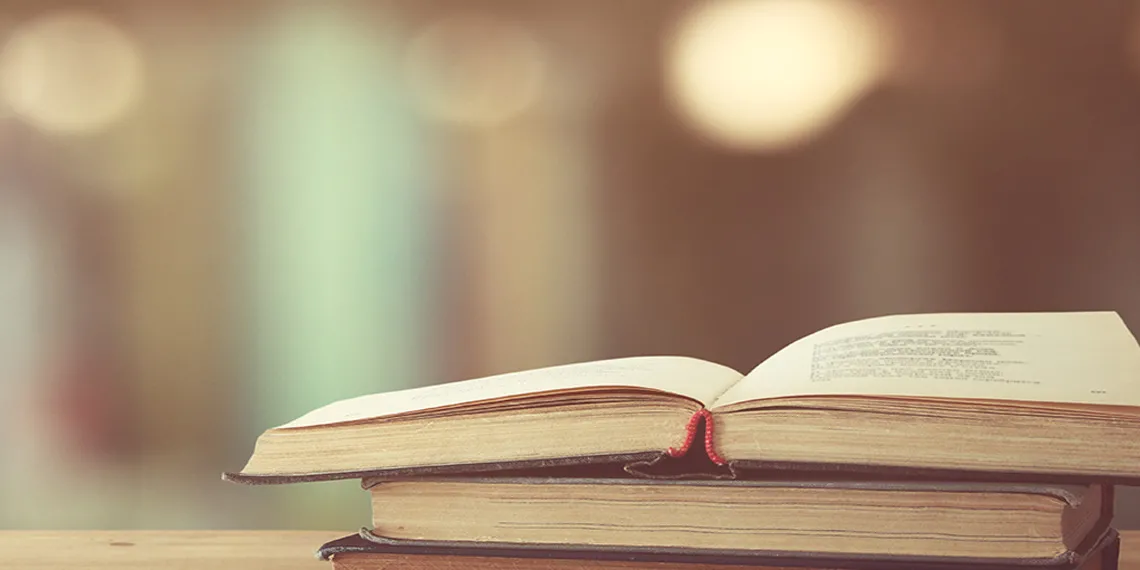 A stack of two books with an open book on top of them.