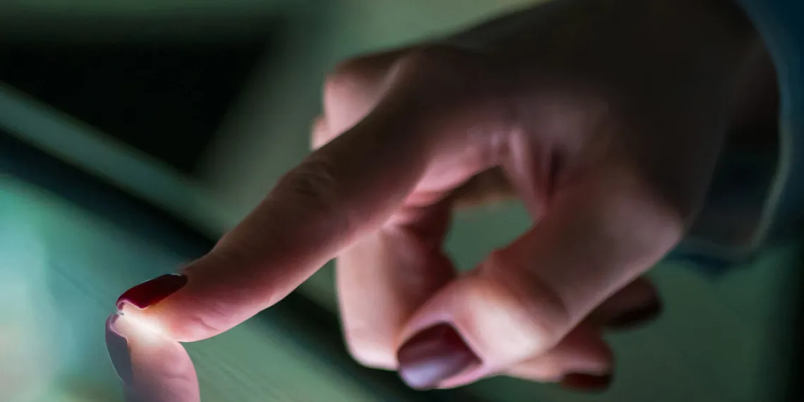 A close-up of a female hand interacting with a touch screen interface.