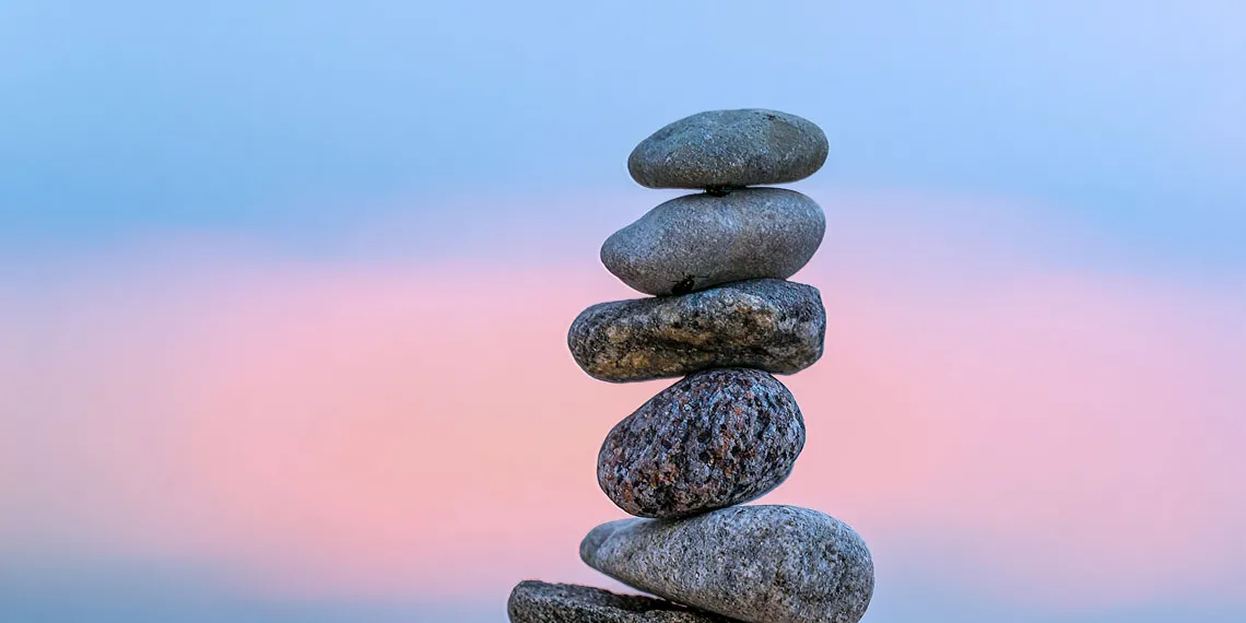A pile of rock cairns sits there with a blue sky in the background.