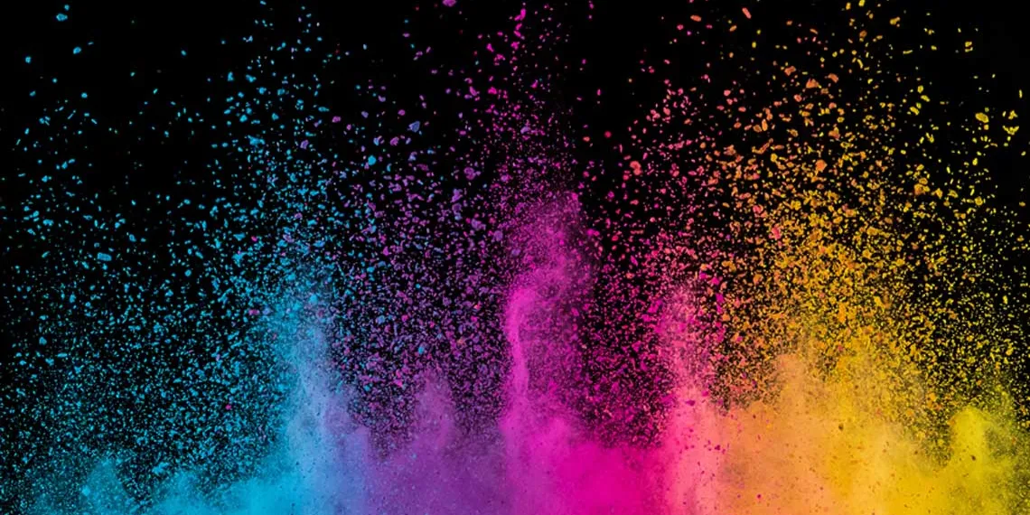 A gradient of powder color dust is being propelled into the air in a dark room.