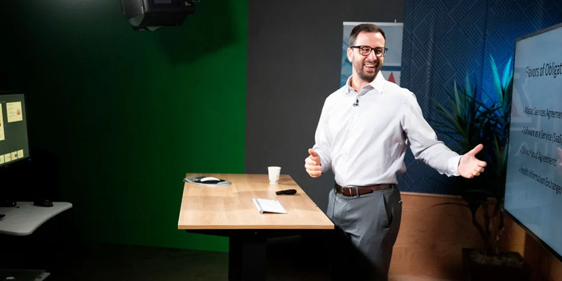 A faculty member smiles while recording an online session at the Harvill studio.