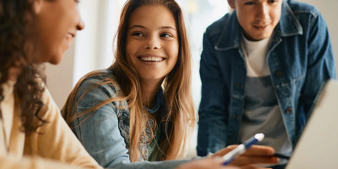 A couple students laugh while they collaborate on a task at a coffee shop.